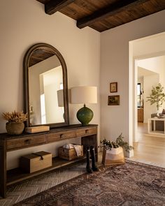 a living room with a large mirror on the wall next to a table and lamp