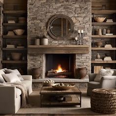 a living room filled with furniture and a fire place in the middle of a stone wall