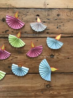 several colorful paper fans are arranged on a wooden surface, with one candle in the middle