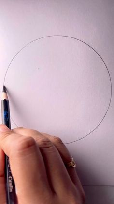 someone is drawing a circle on paper with a pencil