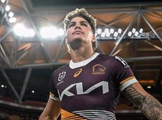 a rugby player standing in the middle of a stadium with his head turned to the side