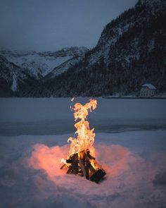 a fire in the snow with mountains in the background