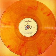 an orange vinyl record with the words sunny fever on it's side, in front of a yellow background