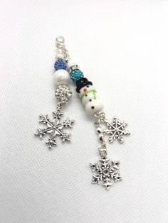 a snowflake keychain with charms attached to it on a white surface