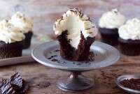 chocolate cupcakes with white frosting on a cake plate