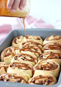 a pan filled with cinnamon rolls and drizzled with caramel on top