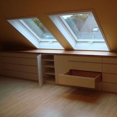 an empty room with two skylights on the roof and drawers in the floor below