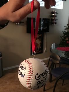 a baseball ornament hanging from a red ribbon in someone's living room