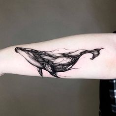 a woman's arm with a black and white whale tattoo on the left forearm