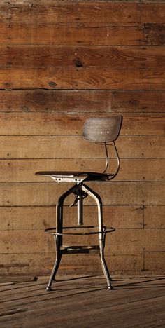 an office chair sitting on top of a wooden floor in front of a wood wall