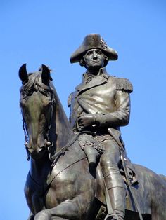 a statue of a man riding on the back of a horse in front of a blue sky