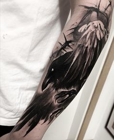 a man with a black crow tattoo on his arm