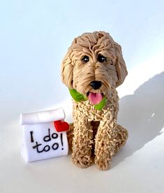 a dog figurine sitting next to a mug with i do too written on it