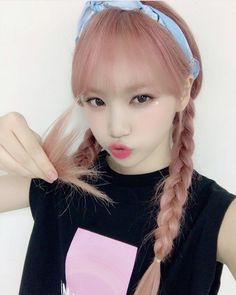 a girl with pink hair is wearing a black shirt and has her hand on her head