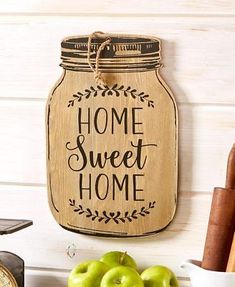 a wooden sign that says home sweet home next to some apples and spices on a table