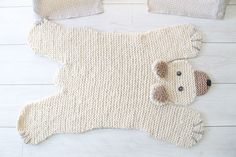 two knitted teddy bears laying next to each other on a white wooden floor,