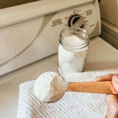 a person holding a spoon with powdered sugar on it in front of a washer