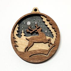 a wooden ornament with an image of a deer in the snow and stars