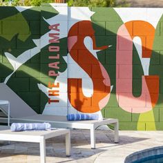 an outdoor pool area with chairs and a mural on the wall