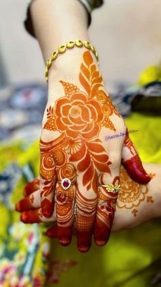 a woman's hand with henna tattoos on her arm and hands, all painted orange