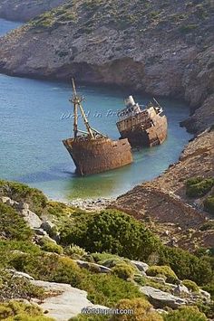 an old ship sitting in the middle of some water