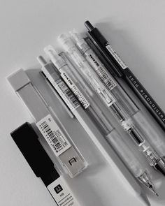 several different pens are lined up next to each other on a white surface with black and white labels