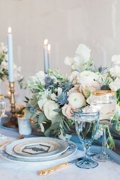 the table is set with white flowers and blue candles for an elegant dinner party or special occasion