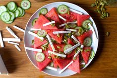 watermelon and cucumber salad with toothpicks on a white plate