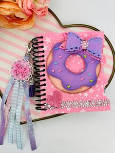 a cookie decorated like a donut on top of a pink and white striped notebook