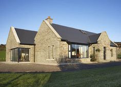 a stone house sitting on top of a lush green field next to a large grass covered field