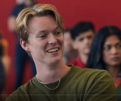 a young man smiling in front of a group of people