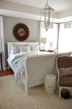 a bedroom with a bed, chair and rug in the corner next to a window