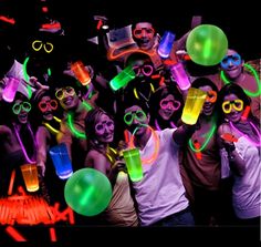 a group of people standing next to each other in front of neon colored glasses and confetti