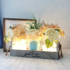 some flowers are sitting in a vase on a table next to a sign that says gather together