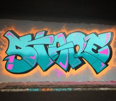 graffiti written on the side of a wall in blue and pink, with black letters