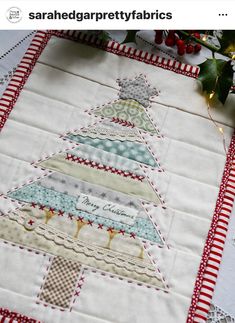 a quilted christmas tree on a table with red and white trim around the edges