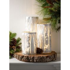 three glass vases sitting on top of a wooden table next to pine cones and evergreen branches