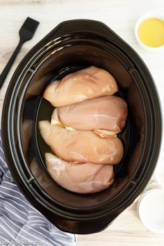 three pieces of raw chicken in a slow cooker, ready to be put into the crock pot