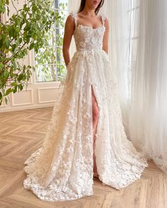 a woman standing in front of a window wearing a white dress with flowers on it