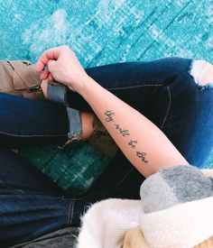 a woman sitting on the floor with her arm wrapped around her leg and writing on it