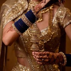 a woman in a gold and blue bridal outfit with her hands on the wrist