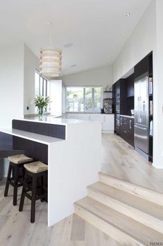 a modern kitchen with white walls and wood flooring on the stairs leading to an island