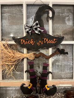 a sign that says trick or treat hanging from the side of a window with witch boots on it