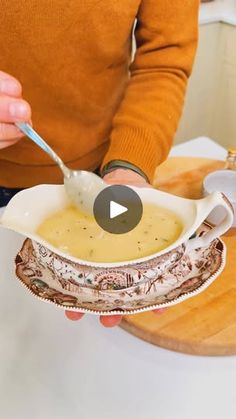 a woman is holding a bowl of soup with a spoon in it and the video appears to be being viewed