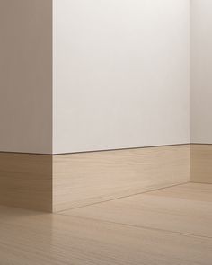 an empty room with white walls and wood flooring on the side, in front of a plain wall