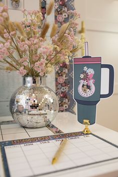 a vase filled with pink flowers sitting on top of a table next to a mirror ball