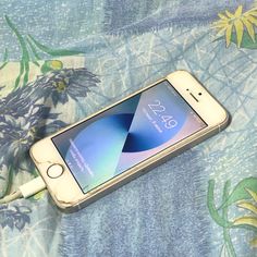 an iphone is plugged in to a charger on a flowery cloth covered surface