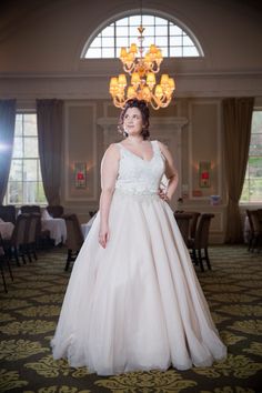 a woman in a wedding dress posing for the camera with a chandelier behind her