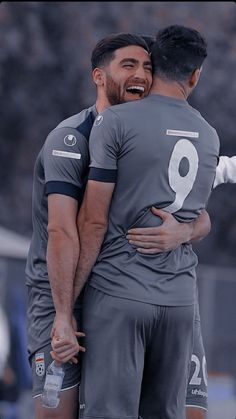 two soccer players are hugging each other while they both have their arms around each other