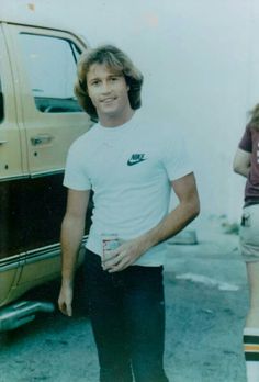 a man standing next to a woman in front of a van and holding a drink